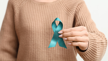 Woman holding teal awareness ribbon for sexual abuse survivors.