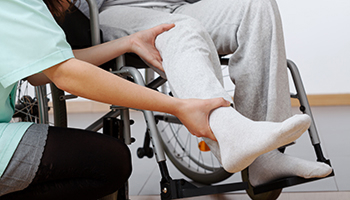 Caregiver assisting injured person seated in a wheelchair.