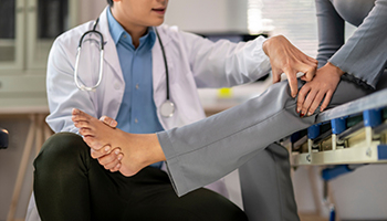Doctor examining patient’s injured leg in a medical office.